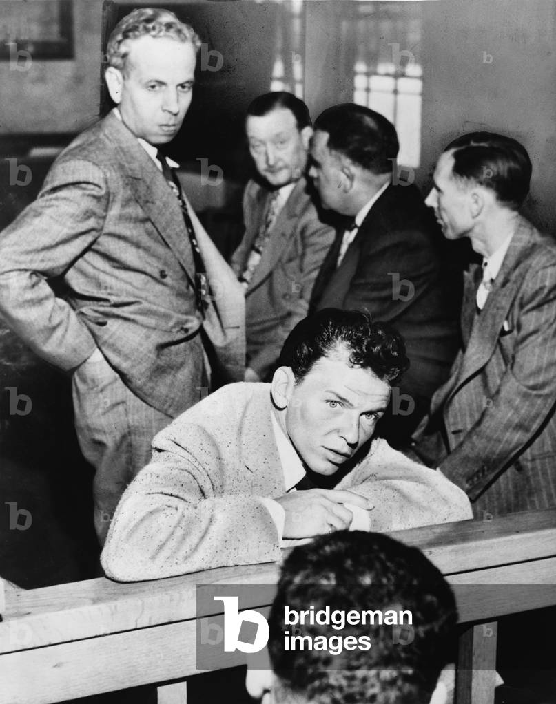 Frank Sinatra (1915-1998) talking with reporters during his trial for battery against journalist Lee Mortimer. Mortimer is behind Sinatra, on left side of photo. 1947