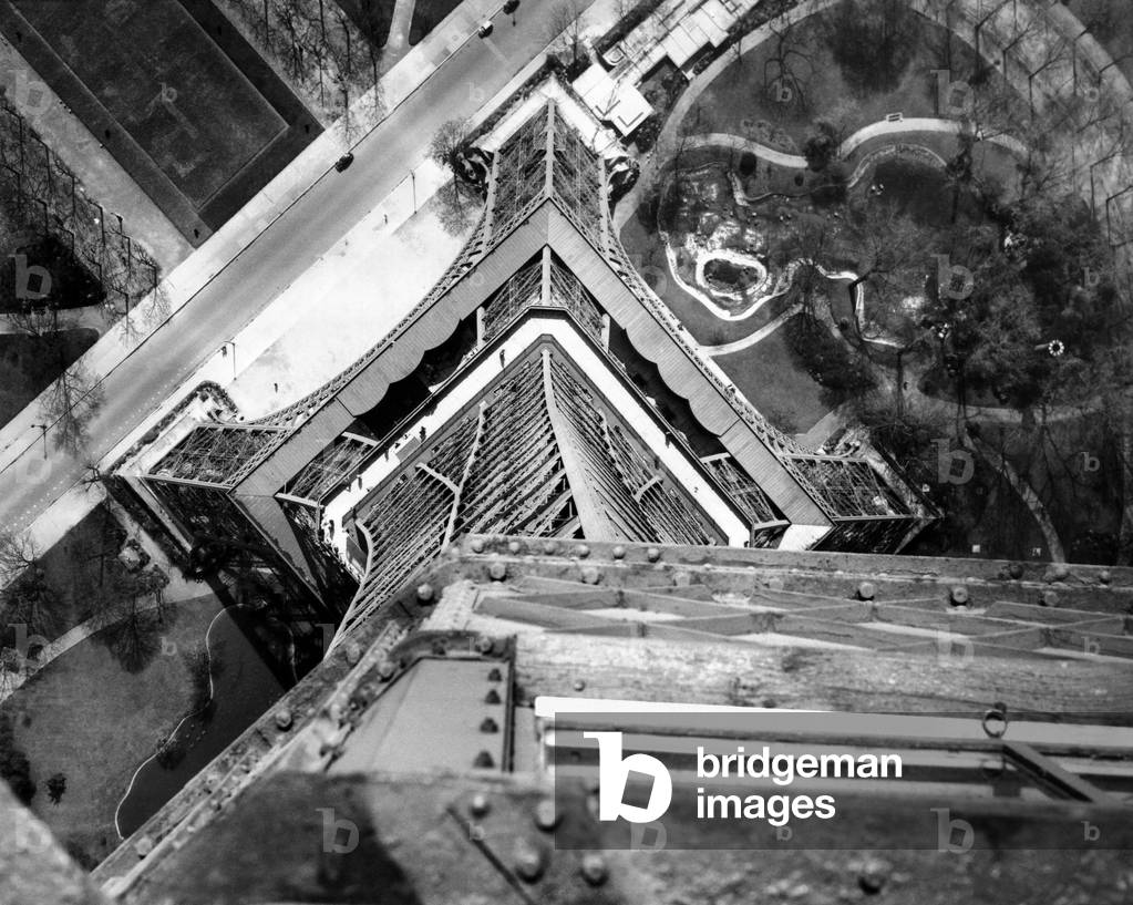 View to the ground from the heights of the Eiffel Tower. Looking down from the third platform shows a maze of steel and the Champ de Mars Gardens. April 16, 1951