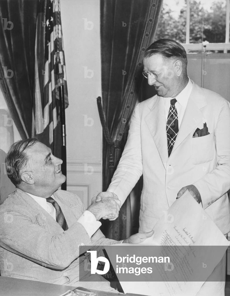 President Franklin Roosevelt congratulates his new Navy Secretary, Republican Frank Knox. After World War II began in Europe, FDR established a bi-partisan Cabinet, including Knox who was the 1936 Republican candidate for Vice President