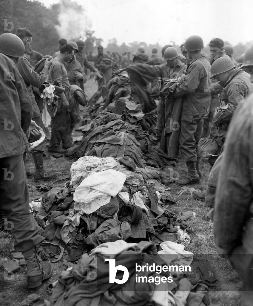 U.S. Soldiers change clothing en masse on wash day during the Normandy Campaign, July 1944. Vapor at the foot of the hedge may be condensation from washing machines. France, World War 2