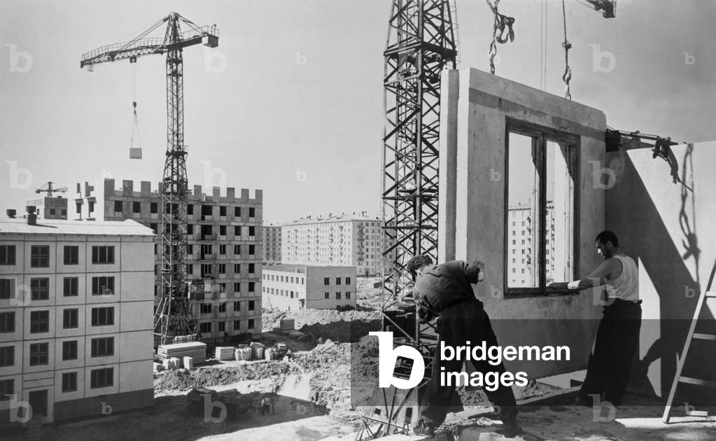Construction workers building an eighty unit apartment building, Moscow, Russia. Workers from N. Kulikov's brigade are setting a pre-fabricated section in place on the fifth story. June 1960.