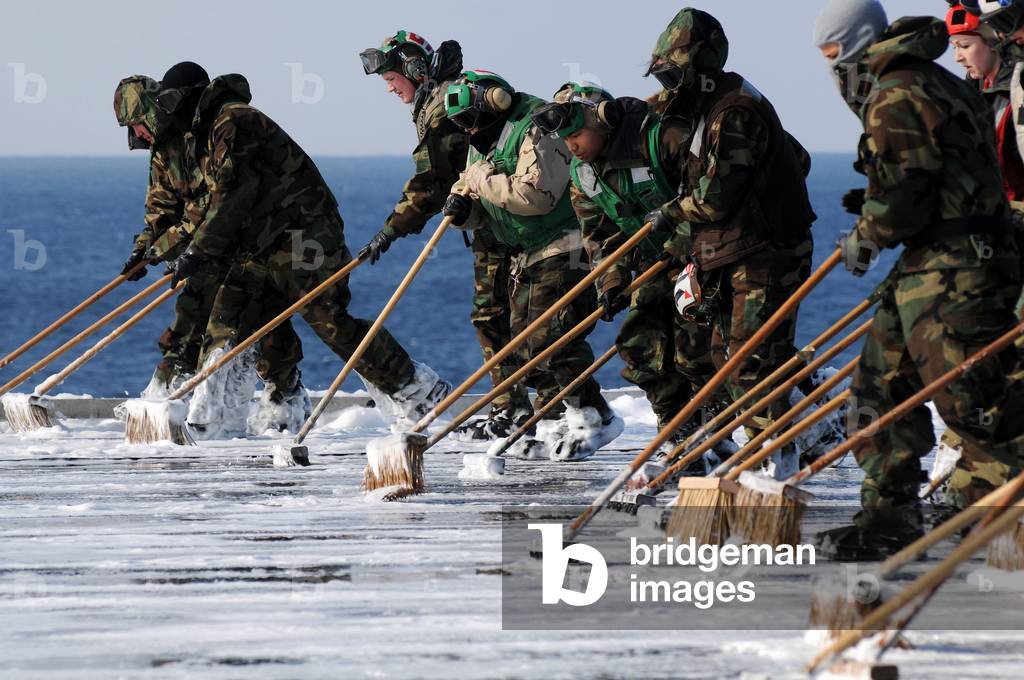 Sailors scrub the flight deck of the USS Ronald Reagan after contamination by radioactive fallout from tsunami damaged nuclear power plants. March 23 2011.,