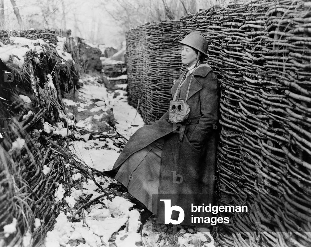 Photojournalist Helen Johns Kirtland in trench during World War I. 1917-18. She wears a trench during, helmet and has a gas mask hanging around her neck