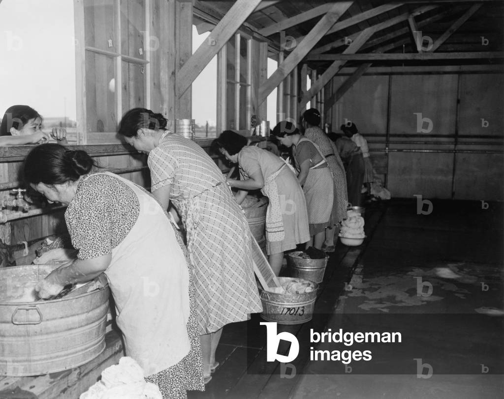 Japanese American women, laundering their families' clothes in metal washtubs during their three month incarceration at Pinedale Assembly Center. 4,823 internees were later sent to permanent internment camps for the duration of World War II. c. April 1942