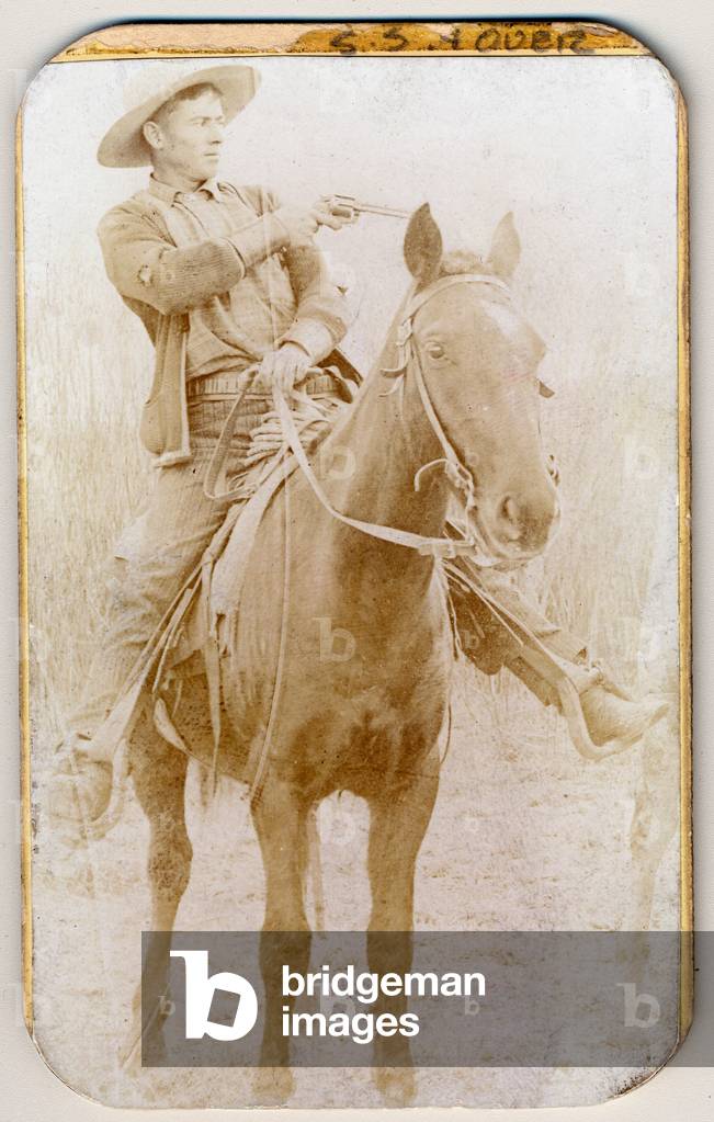 Wild West. Will Roberts, alias Dixon, cowboy train robber, seated on a horse, pointing a gun, 1900