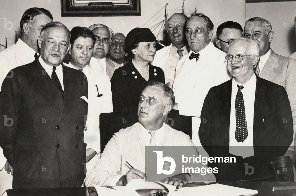 President Franklin Roosevelt signing the Social Security Act. Among those with the President are Sen. Alben Barkley, Sen. Robert Wagner, Sen. Robert LaFollette, Labor Sec. Frances Perkins, Rep. Pat Harrison, and Rep. David Lewis. August 18, 1935