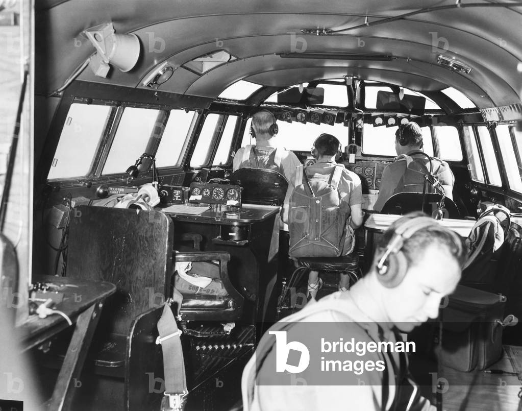 The bridge deck or cabin of the 82-ton Douglas B-19, the world's largest bomber. Nov. 13, 1941. With backs to camera are the pilot, flight engineer, and co-pilot. The radioman is at lower right. The two empty chairs are for the navigator and the commander. The plane never went into production and was superseded by the B-29