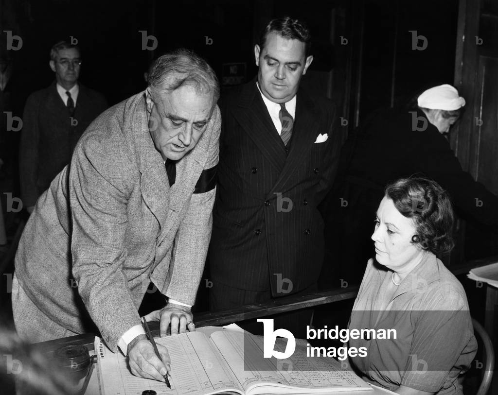 President Franklin D. Roosevelt, the Presidential aid Thomas Qualters, and Emma Crapser, as the President signs the register in a local election in Hyde Park, New York, November 4, 1941