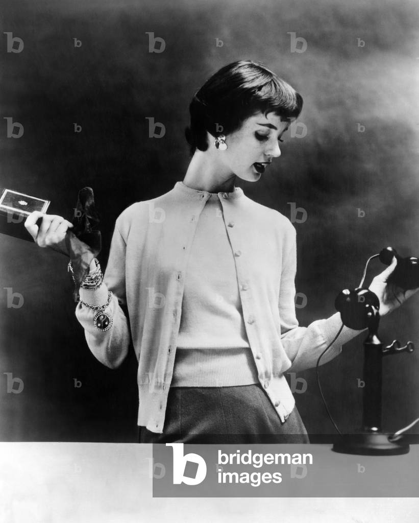 Sweater set of the 1950s. The 1955 fashion photo is staged with a 1920s telephone to emphasize the sweaters' timelessness