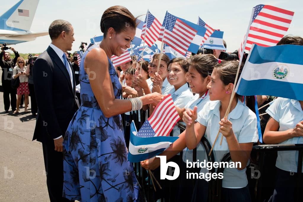 President and Michelle Obama greet children during the arrival ceremony at Comalapa International Airport in San Salvador. Michelle wears a printed Jason Wu dress accessorized with an Alexis Bittar pin. March 22 2011. (BSWH_2011_8_278)