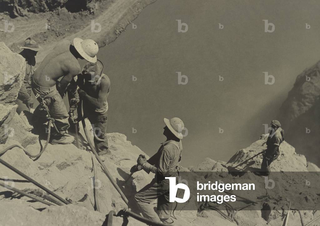 Workers at Boulder Dam site in 1934. They are high scalers drilling on canyon walls above the Colorado River