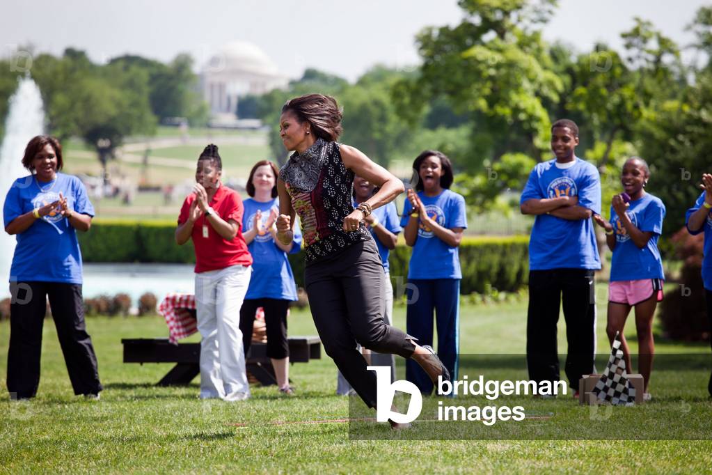 First Lady Michelle Obama participates in the Pit Crew Challenge during an event with the President's Council on Fitness Sports and Nutrition on the South Lawn of the White House May 9 2011 (photo)