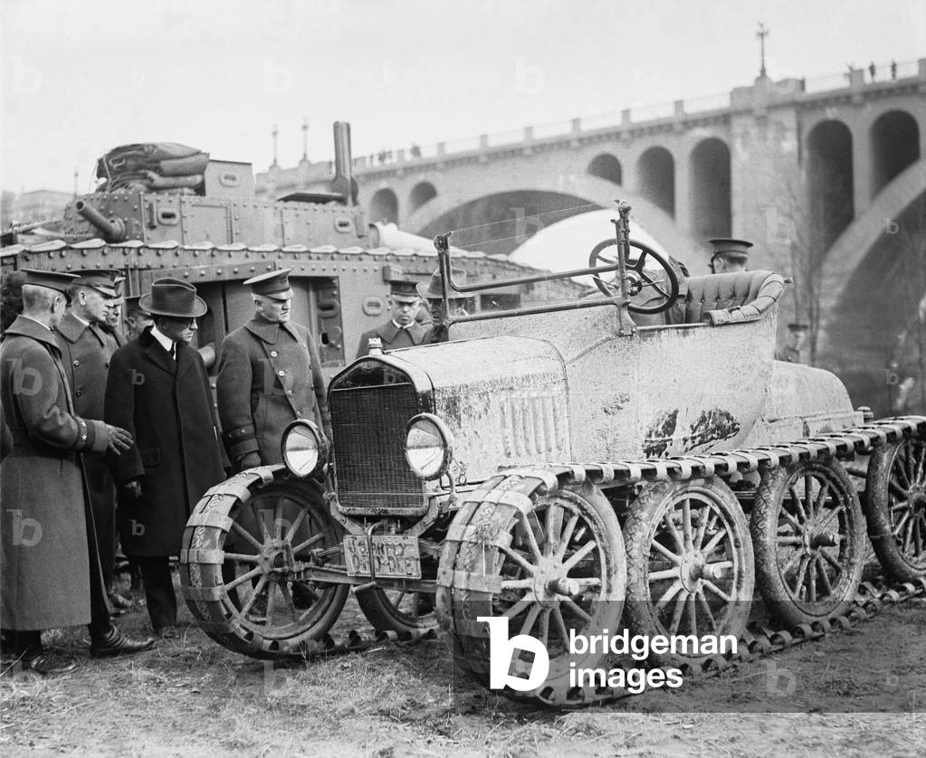 Henry Ford (1963-1947), and Military officers, inspect a multi-wheeled vehicle with caterpillar tracks. 1921