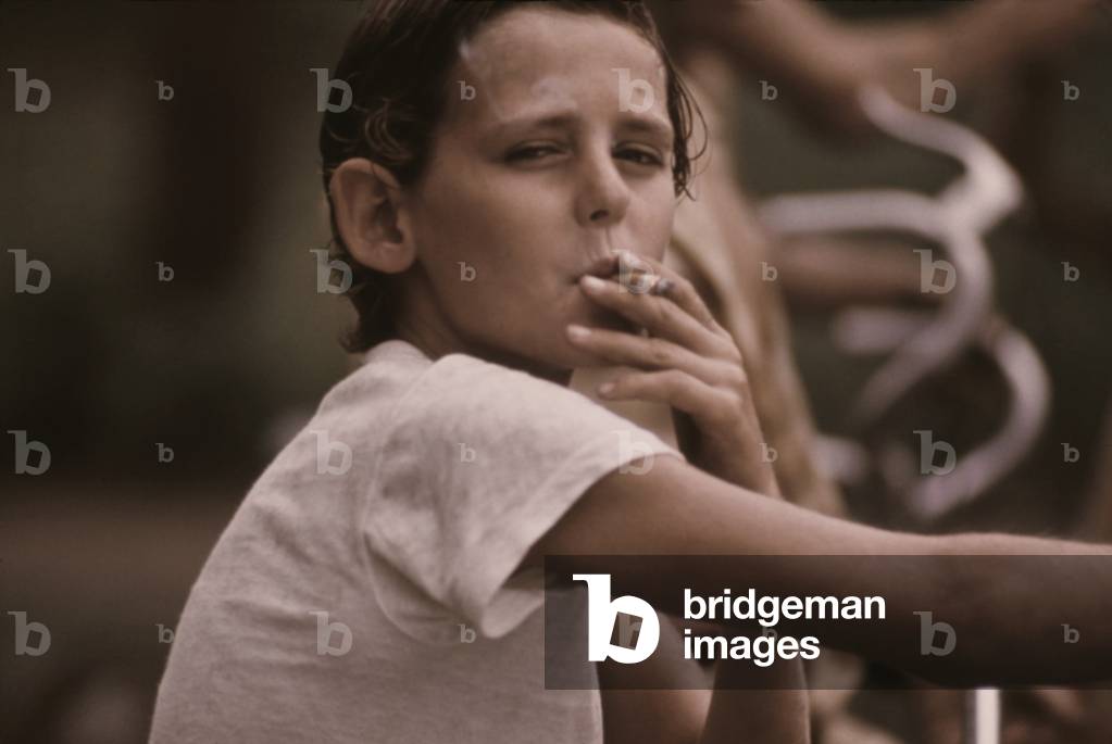 A pre-teen boy smoking a cigarette on Kansas City's west side. c. 1973-75