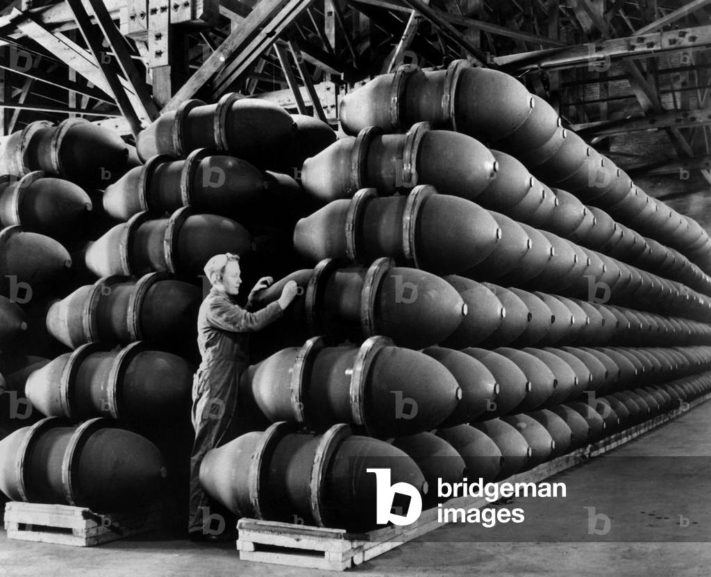 Woman war worker checks 1,000 lb. bomb cases loaded with explosives. Firestone Tire and Rubber Co., Omaha, Nebraska. May 1943 during World War 2