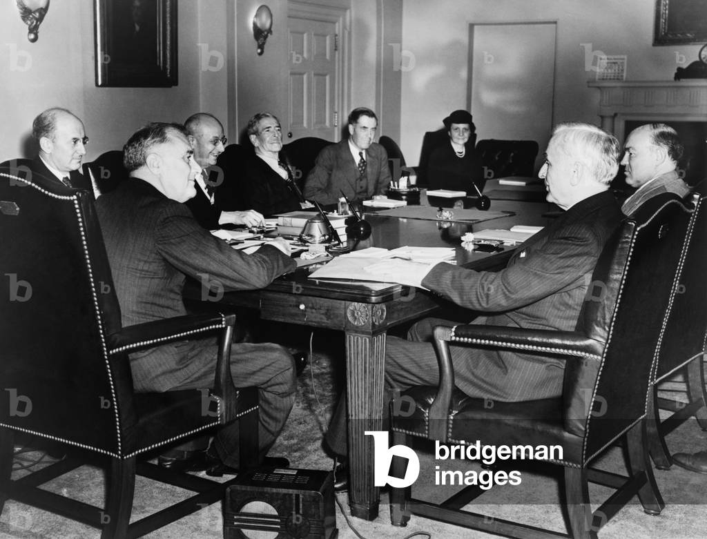 Pres. Franklin Roosevelt meets with cabinet in emergency session. 1938. Seated clockwise around a table: Franklin D. Roosevelt, Henry Morgenthau, Homer Cummings, Claude A. Swanson, Henry A. Wallace, Frances Perkins, Harry Woodring, and Cordell Hull