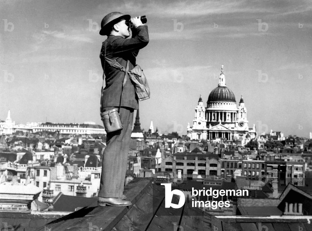 Aircraft spotter searches the sky with binoculars during the Battle of Britain. St. Paul's Cathedral is in the background. World War 2, c. 1940-41