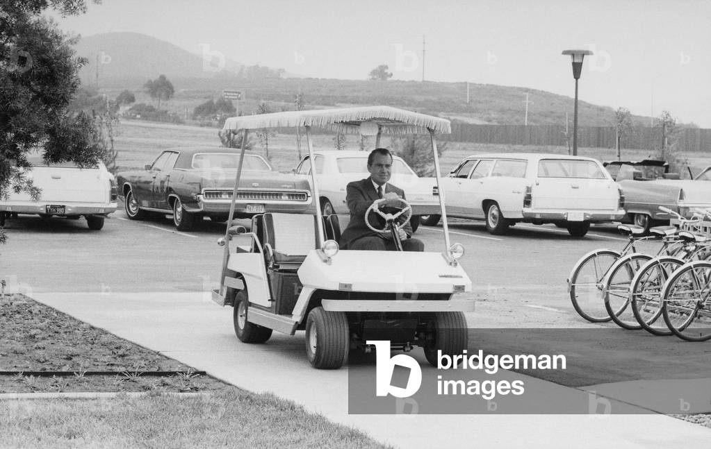 Richard Nixon driving a golf cart in a sidewalk to the helipad at San Clemente. c. 1969-74