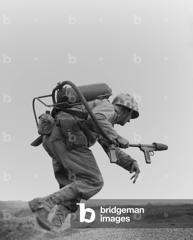 Marine with a flame-thrower, running to assault a Japanese pillbox on Motoyama Airfield Number Two. Iwo Jima. c. Feb. 20-March 16, 1945. World War 2