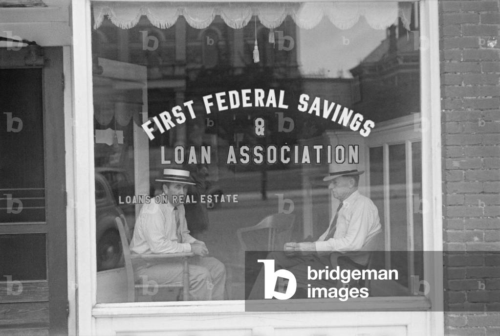Two businessmen sit behind the storefront window of a Marion, Ohio, Savings and Loan Association. The Depression era Federal Home Loan Bank Act of 1932 made low-cost funding available for mortgage lending