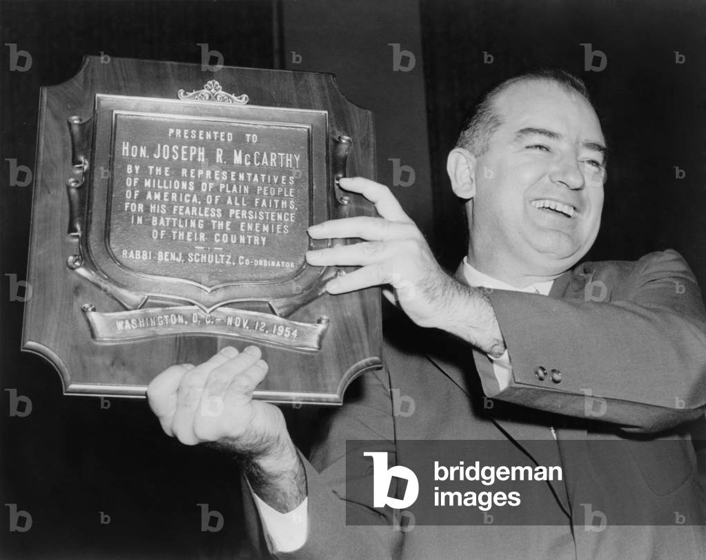 Wisconsin Senator Joseph McCarthy displays a plaque honoring him 'for his fearless persistence in battling the enemies of their country'. Within a month, on December 2, 1954, the Senate voted to censure McCarthy, ending his national influence