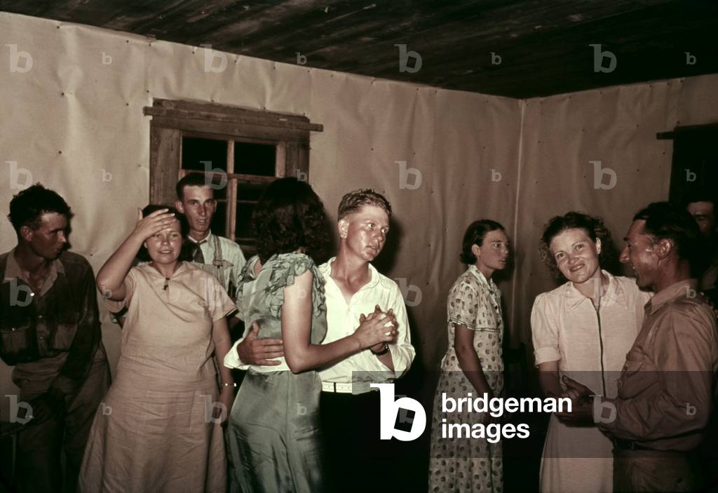 Square dance in rural home in McIntosh County Oklahoma. They dance in a simple interior with butcher paper covered walls. c. 1938-39