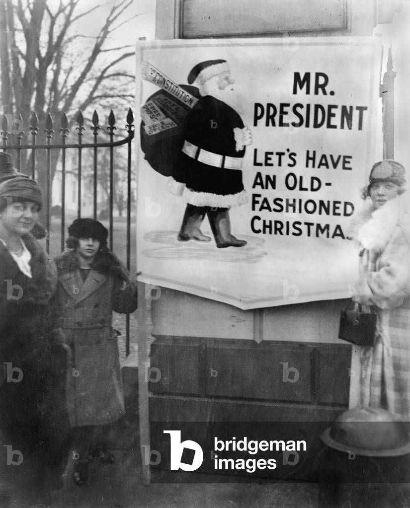Women demonstrators requesting political amnesty outside the White House, The demonstrators' sign says, 'Mr. President, let's have an old-fashioned Christmas,' and shows Santa Claus carrying a bag of gifts including, the Constitution, Free Assemblage, Free Speech, and Free Press, photograph, 1922
