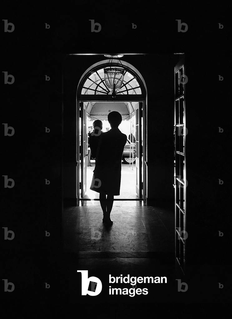 Silhouette portrait of Jacqueline Kennedy carrying her son John Kennedy Jr. in the White House, South Portico Entrance, 1962 (b/w photo)
