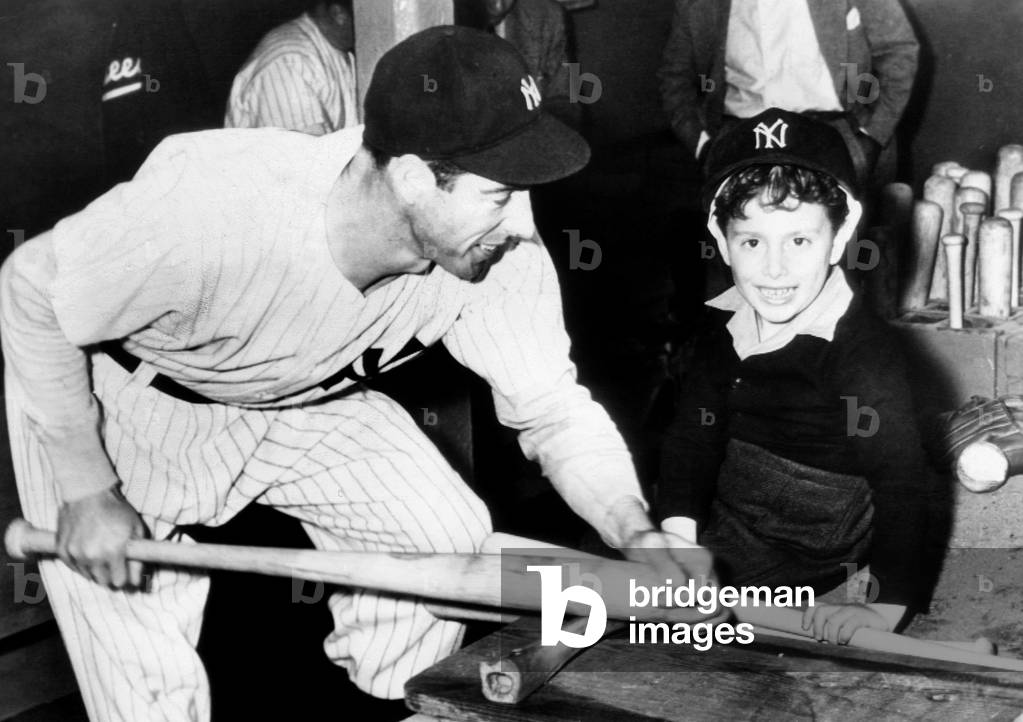 Joe DiMaggio shows his son, Joe Jr., how to bone down a baseball bat, 1946