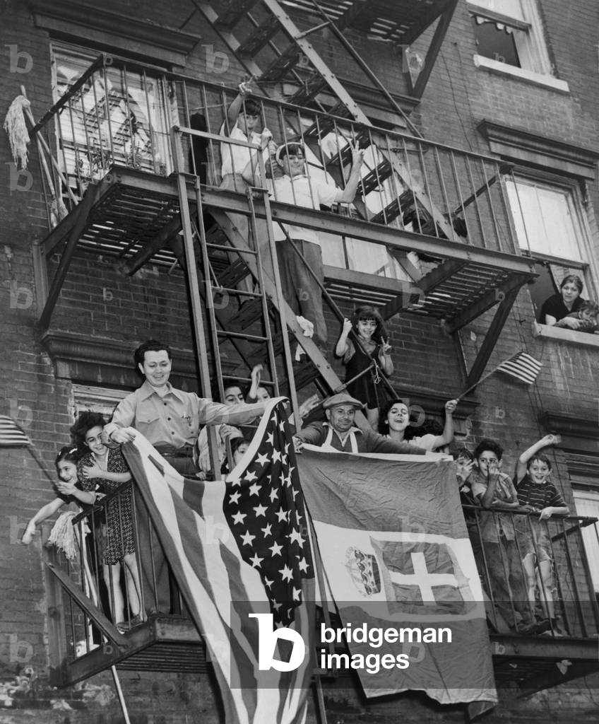 Italian Americans celebrating the armistice between Italy and the Allies. They wave American and Italian flags from their balconies in New York City. Sept. 8, 1943. World War 2