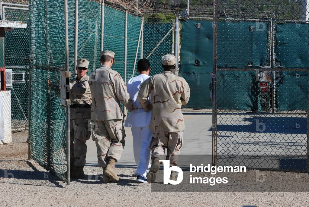 U.S. Navy guards escort a detainee through Camp Delta the military prison for enemy combatants many believed to be associated with Al-Qaeda or the Taliban. June 10 2008., Photo by:Everett Collection