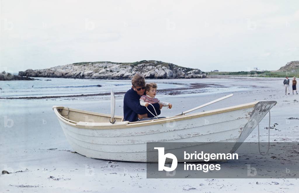 President John Kennedy and John Jr. play in a beached rowboat at Newport, Rhode Island. 1962