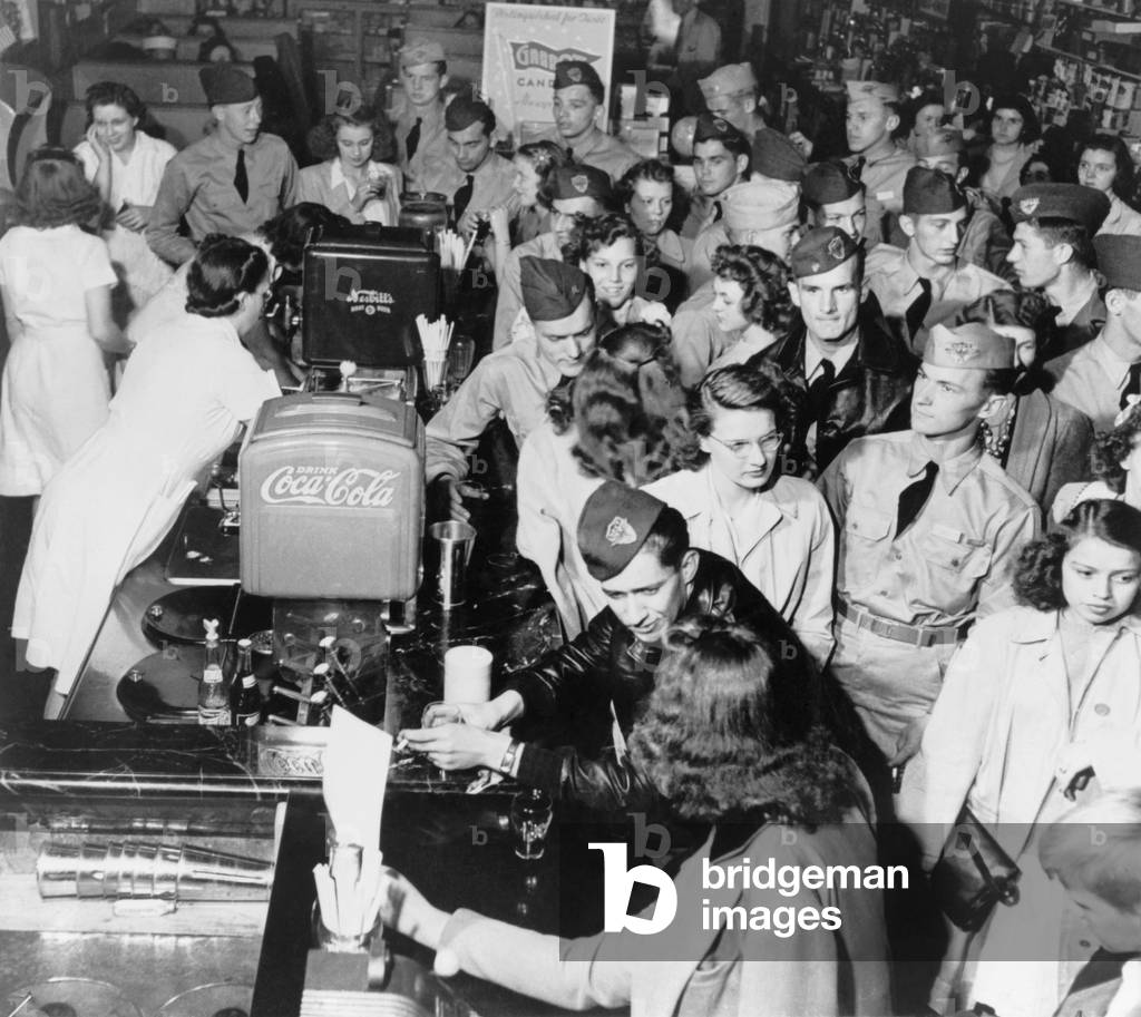 Soldiers on leave with young women in a crowded soda fountain. In Minnesota, during World War 2. c. 1942-45