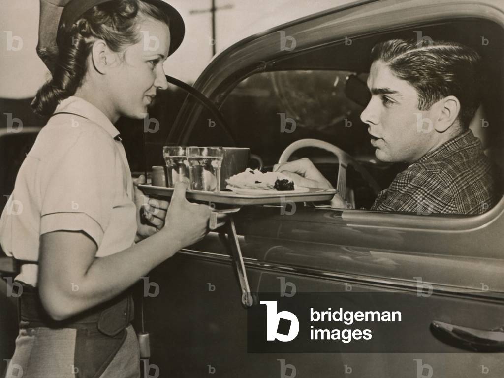 Drive-in restaurant in Hollywood, Los Angeles. June 29, 1938. Waitress brings food to drivers who do not have time to stop at a restaurant.