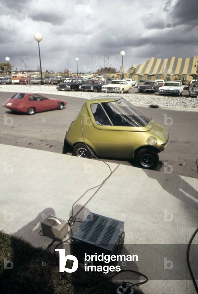 An General Motors urban electric car gets battery charge at a 1973 Environmental Symposium in Ann Arbor Michigan. In the background is the electric SUNDANCER. Oct. 1973