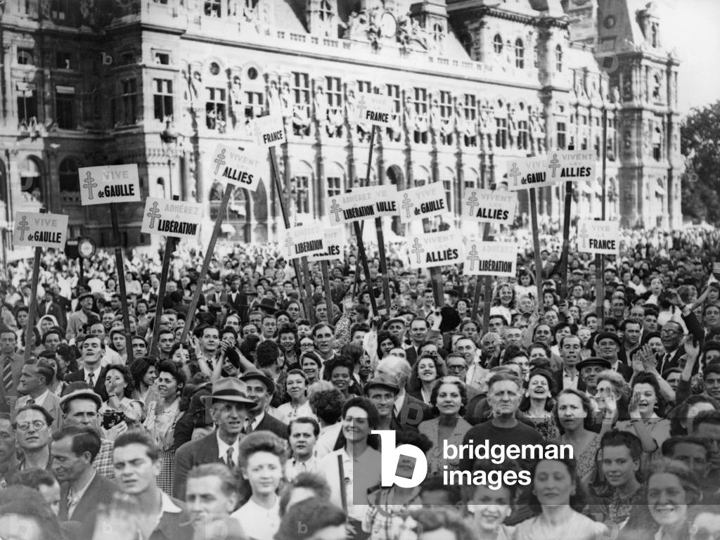 Newly liberated French crowd demonstrate their joy at the Hotel de Ville, Paris, with signs celebrating Charles De Gaulle, the Allies, and French Resistance. 1944