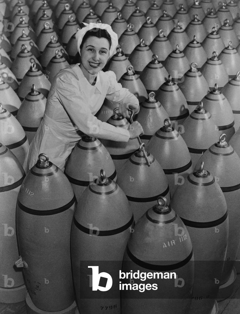 Canadian woman munitions worker tightening the nose plugs on 500-pound aerial bombs. 1942-43, during World War 2