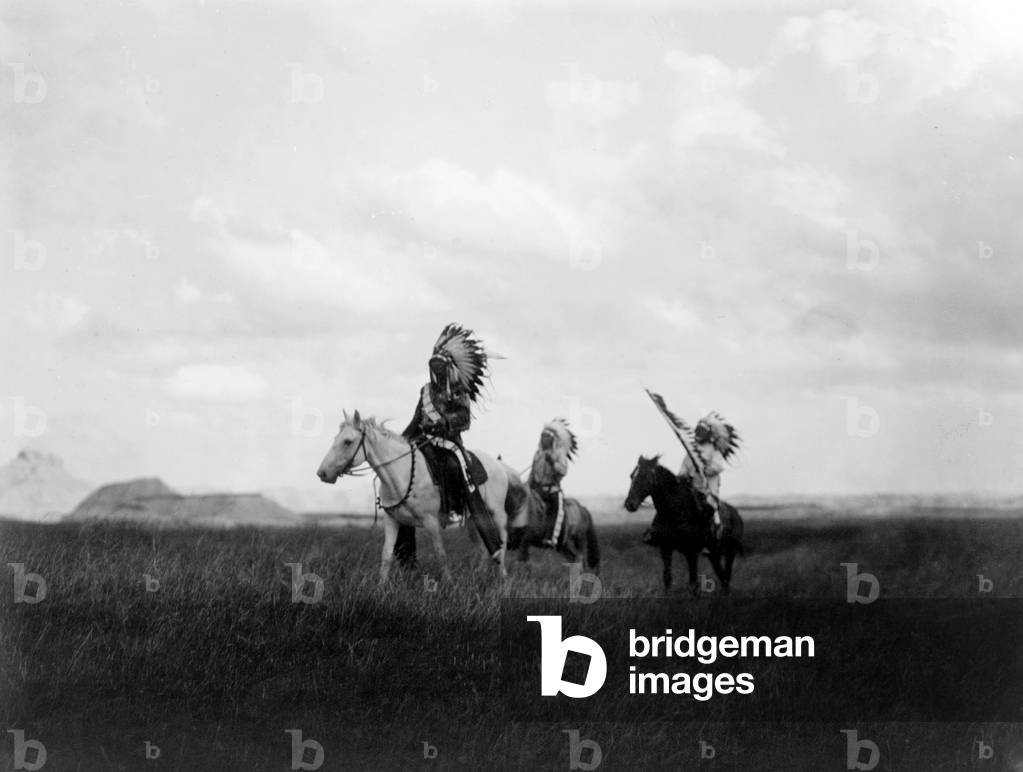 The March of the Sioux, three Sioux Indians on horseback on plains with rock formations in background, photograph by Edward S. Curtis, 1905