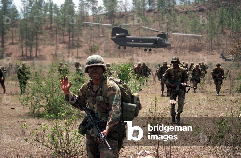 An 82nd Airborne Division soldier signals to his platoon as they advance across a field in Honduras after being inserted by a Chinook helicopter in Tamara Honduras. Honduran and U.S. Army Special Forces conducted exercises to counter Nicaragua's attempts, Photo by:Everett Collection