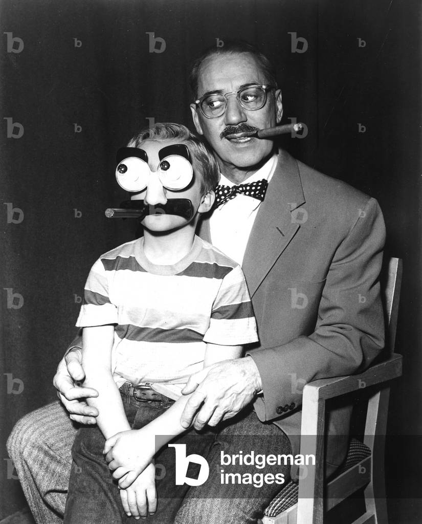 Groucho Marx and a child with a Groucho mask, 1955