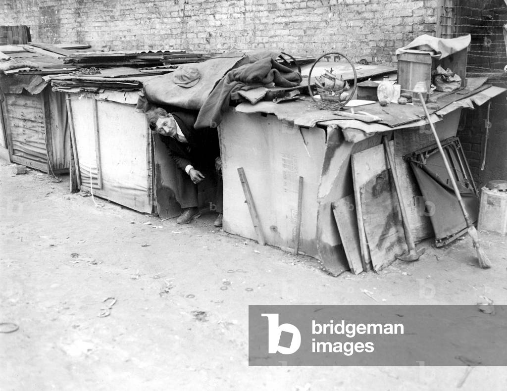 An unemployed man living in a shack constructed from packing cases and pieces of wood in New York City, off Broadway on West Houston Street. February 8, 1933.