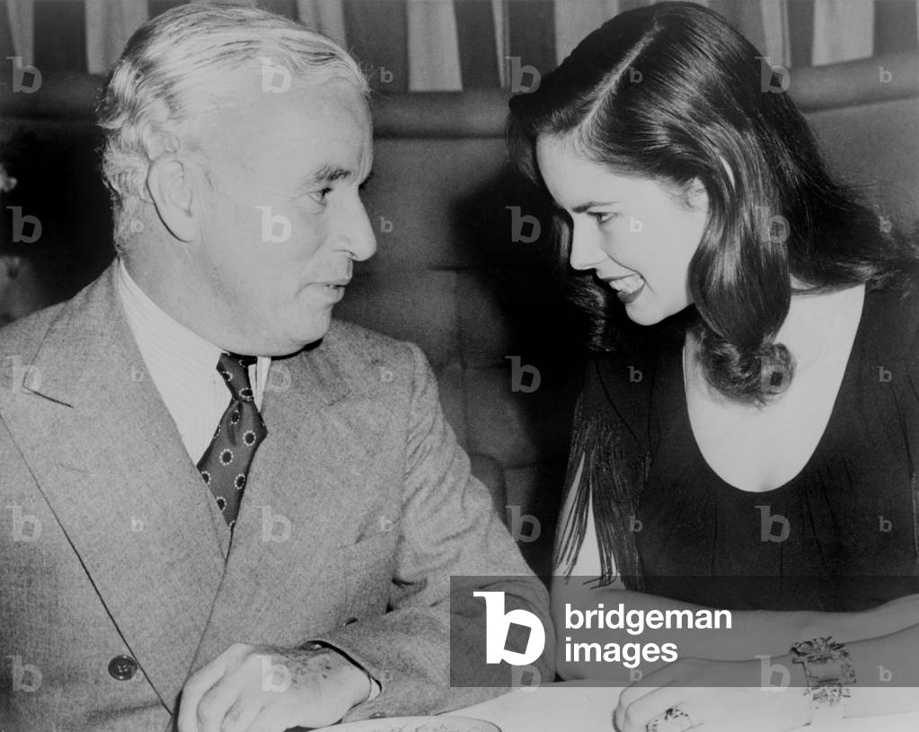Charlie Chaplin sitting with his young wife Oona at Hollywood nightclub in 1944 (photo)