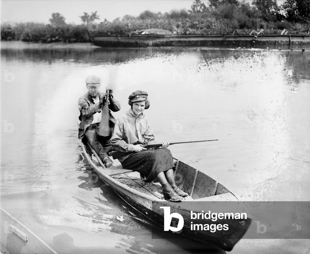 Man and woman in a canoe, the woman holds a gun, 1921