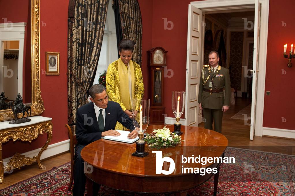 President Obama and Michelle Obama sign the guest book at Slottet Royal Palace of Norway in Oslo Norway. Michelle wears a sulfite laser cut velvet dress and jacket designed by Francisco Costa for Calvin Klein's Fall 2009 collection. Dec. 10 2009,