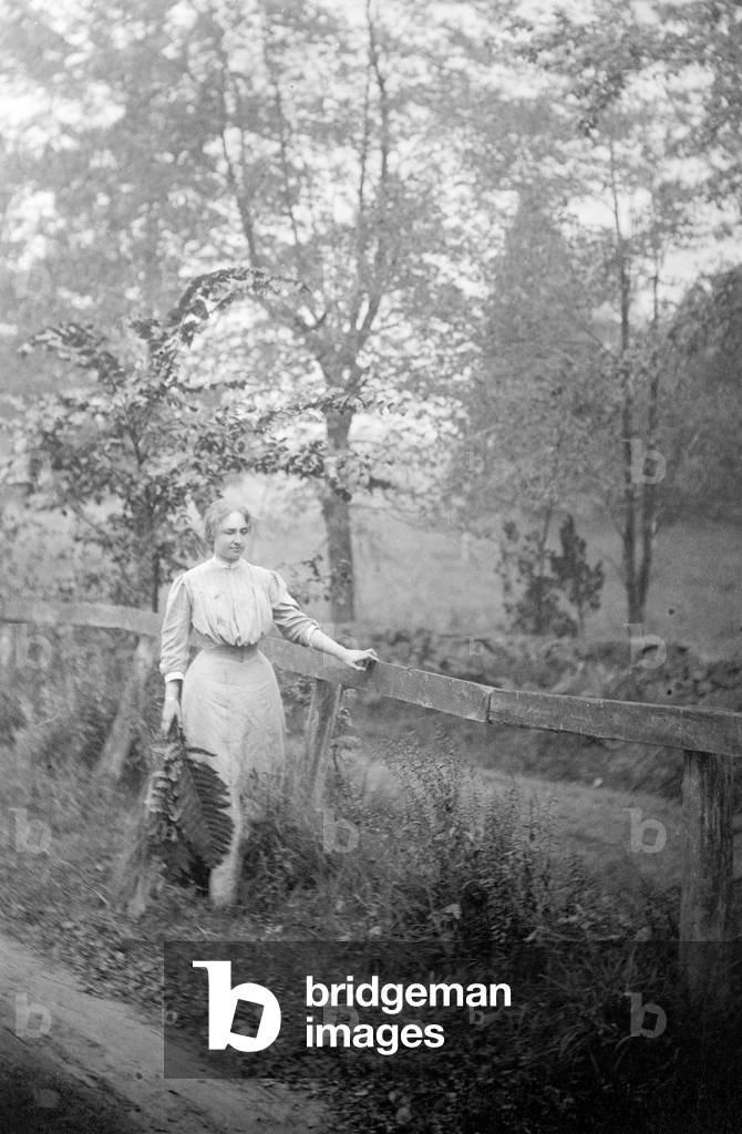 Helen Keller (1880-1968), blind and deaf since age 2, walking by fence, holding fern leaves, in 1907. g by fence, holding fern leaves, in 1907. g by fence, holding fern leaves, in 1907