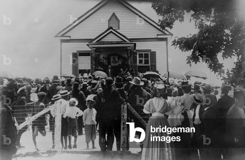 Booker T. Washington addressing crowd from porch of a small building, in Brownsville, Texas, c. 1900