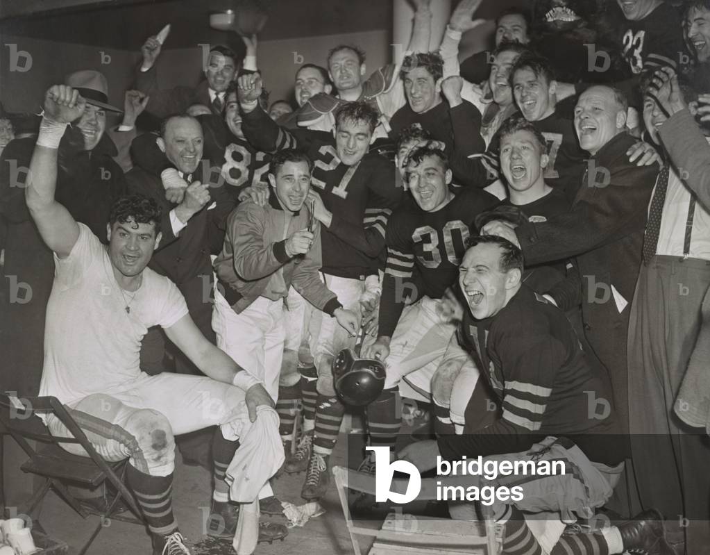 Chicago Bears cheering after beating the Green Bay Packers in the western division playoffs. 2nd from left, standing, is owner-coach George Halas. At far right is line coach Hartley 'Hunk' Anderson.