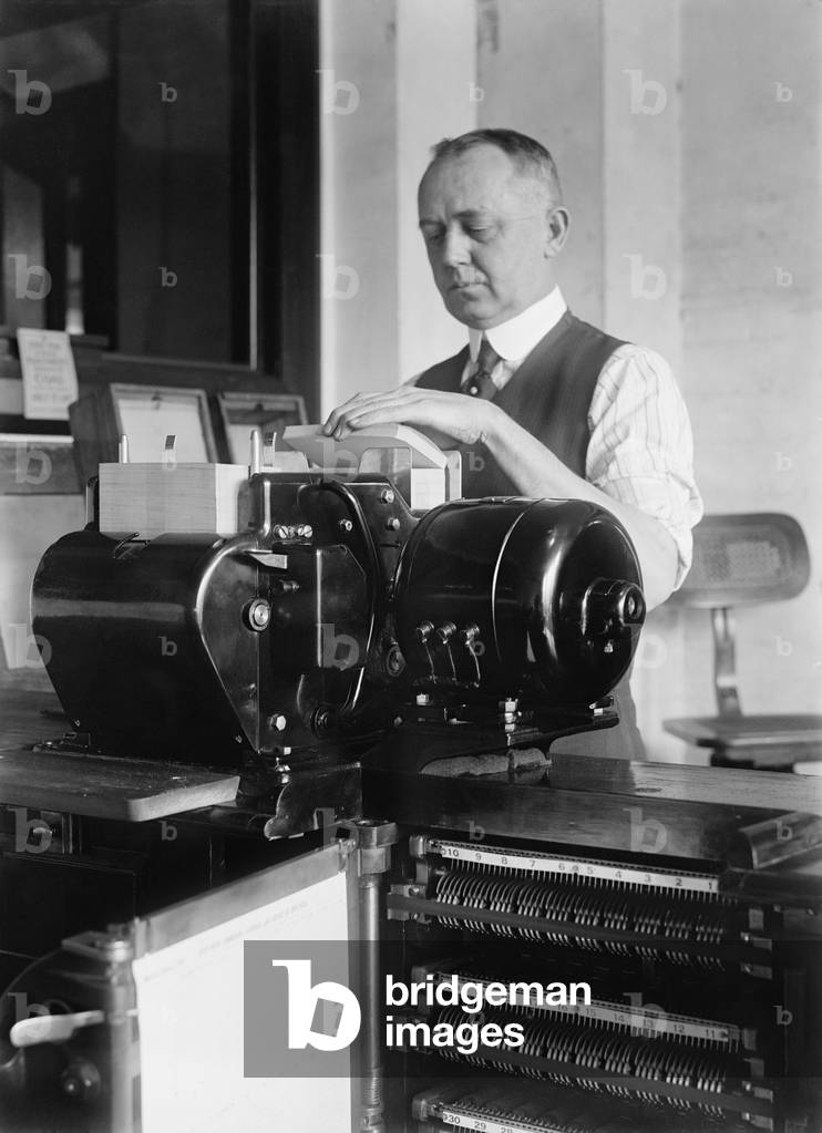 Man loading punch cards into a tabulating machine used in the 1920 United States census. It was a predecessor of electronic computers, and worked by mechanically reading punch cards with coded information