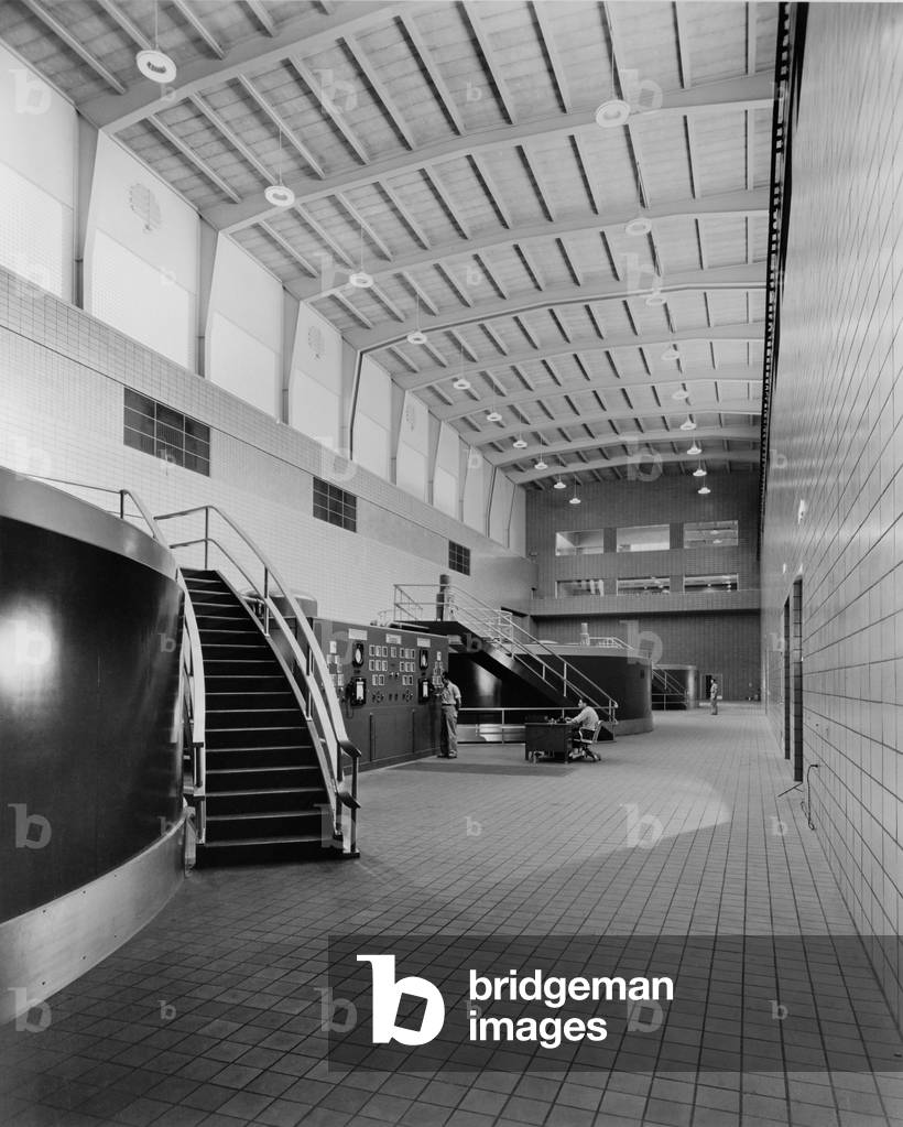 Two men at the control panel of the Chickamauga Dam are dwarfed by the large scale of the generator hall. 1940