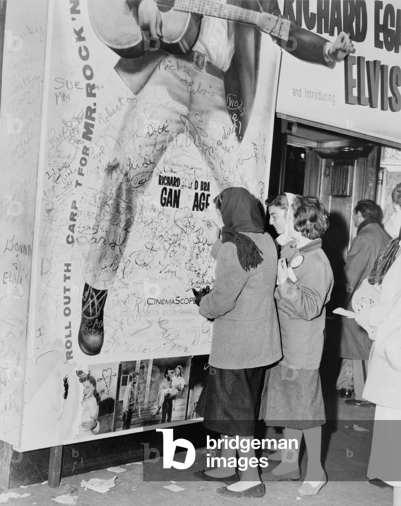 Teenage girls add graffitti to LOVE ME TENDER movie poster, Elvis Presley's film debut. 1956